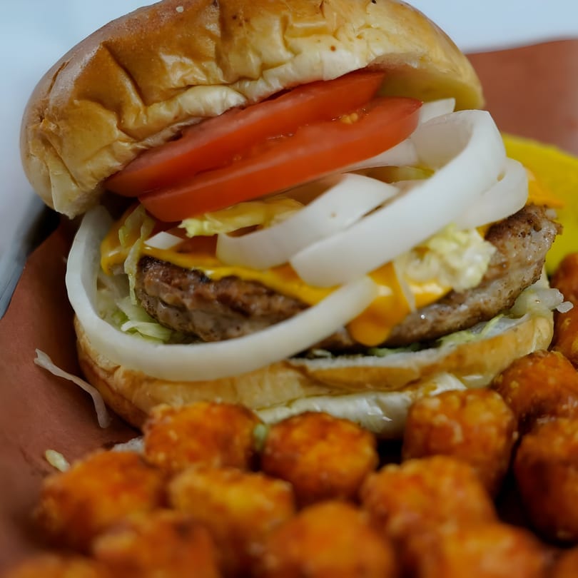 A GB's Pub & Grub cheeseburger with tomato, onion, lettuce, and tater tots.