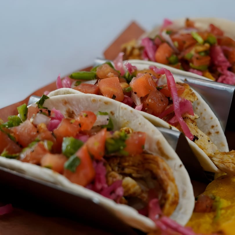 Three GB's Pub & Grub tacos filled with chicken, diced tomatoes, green peppers, and pickled red onions.